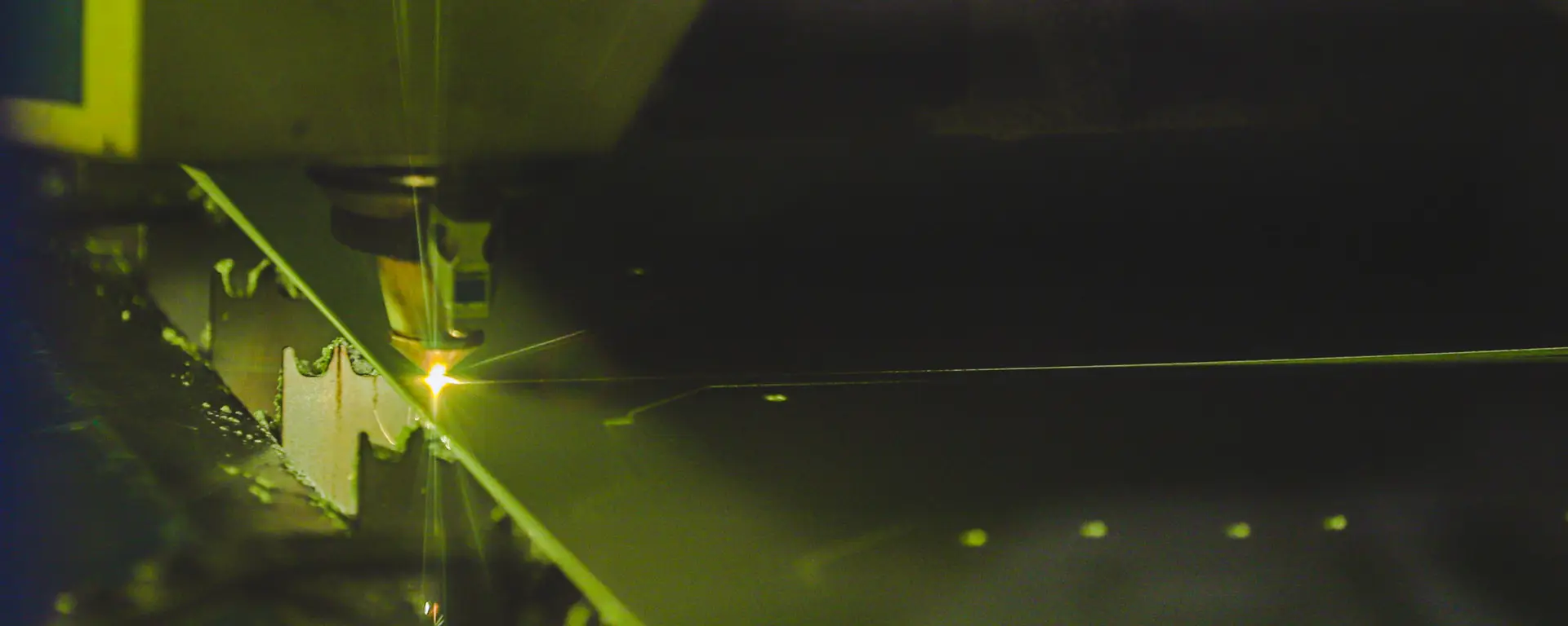 Lasern einer Metallplatte, auf dem Bild der Laser und grünlicher Lichtstrahl